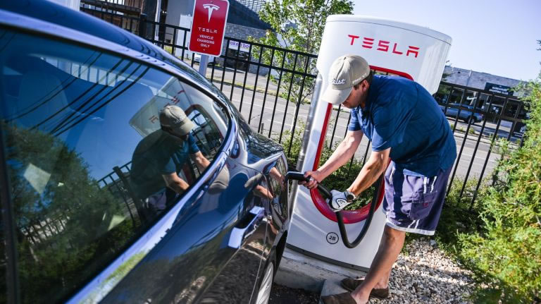 Jeff Wheeler, of Amityville, plugs in his Tesla Model 75S at the Tesla charging station at Country Pointe Plainview on Tuesday. Photo Credit: Newsday/Steve Pfost